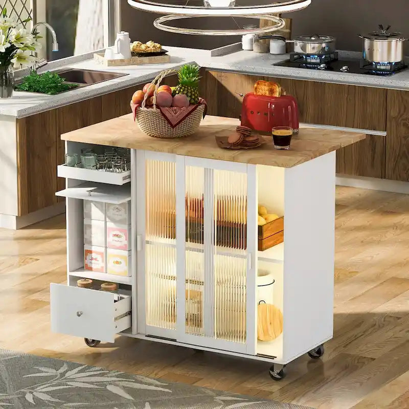 Îlot de cuisine avec surface à rabat, éclairage LED, portes en verre cannelé, étagère réglable, deux tiroirs et roulettes.